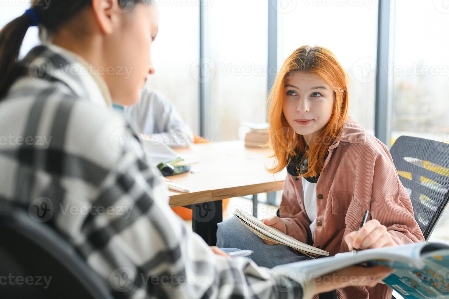 students sitting in a classroom, studying, discussing photo
