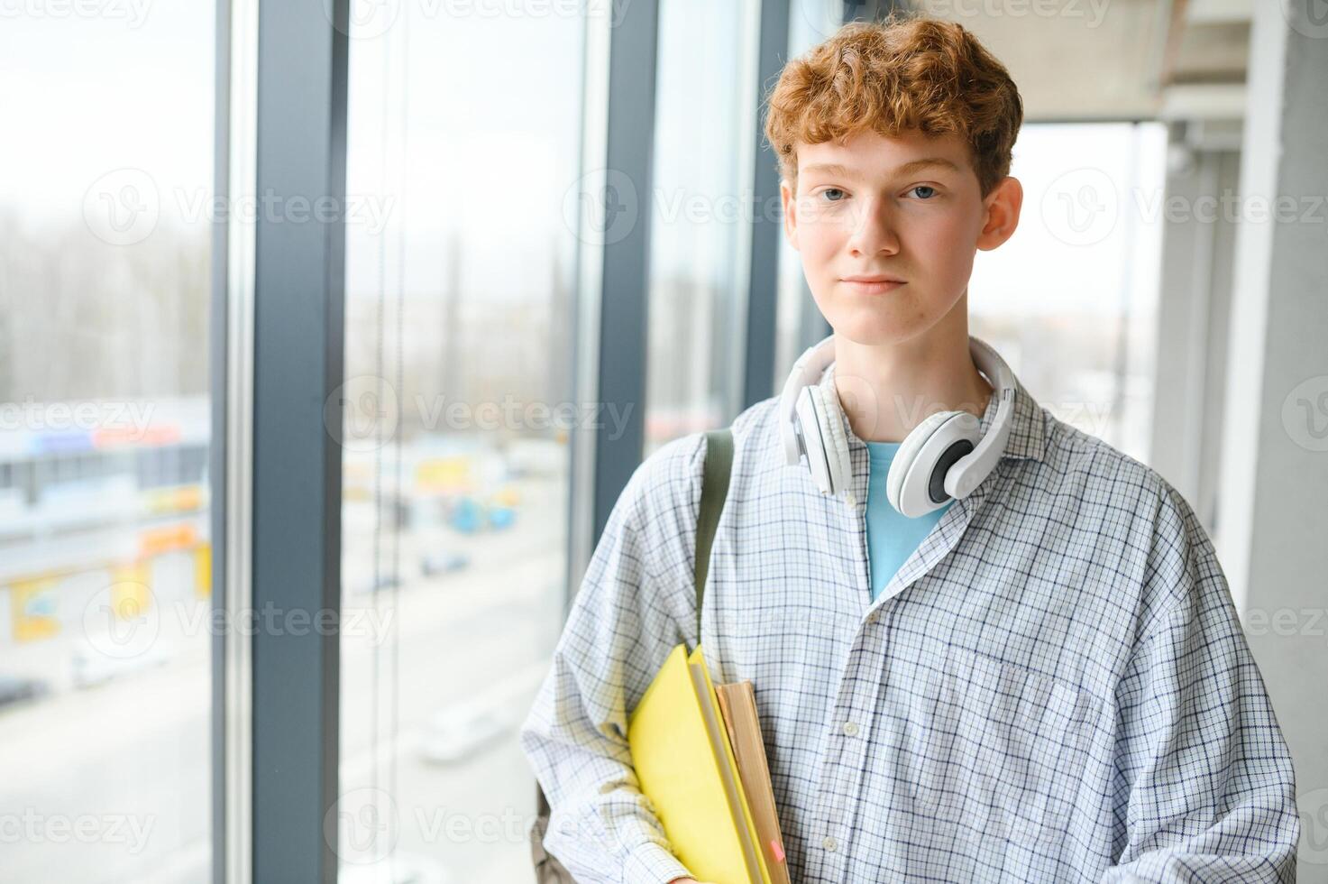 A young guy college student with a backpack is standing in the hall of the university photo