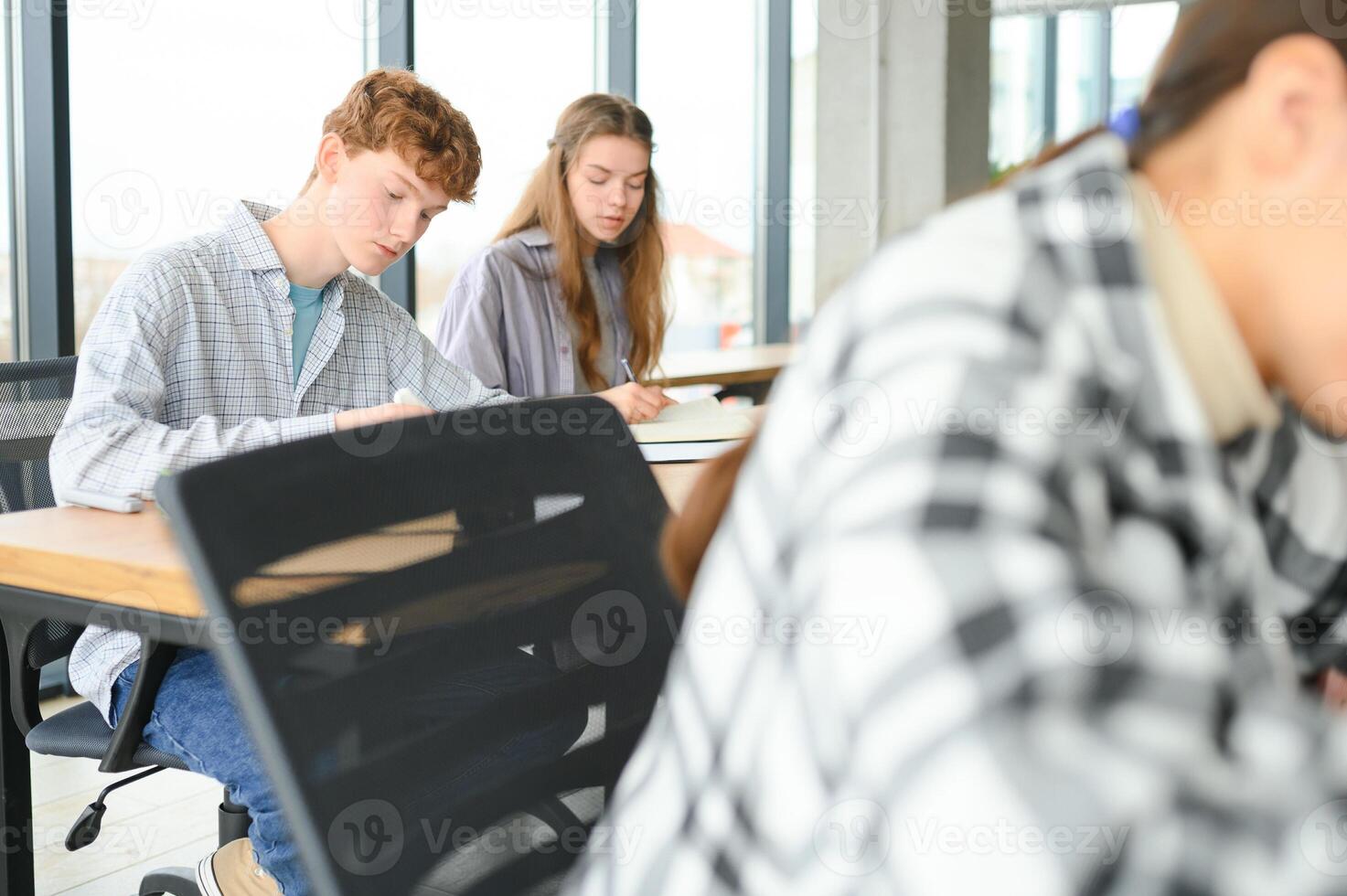 Testing. Closeup of young students sitting in a row and having test in their test-books photo