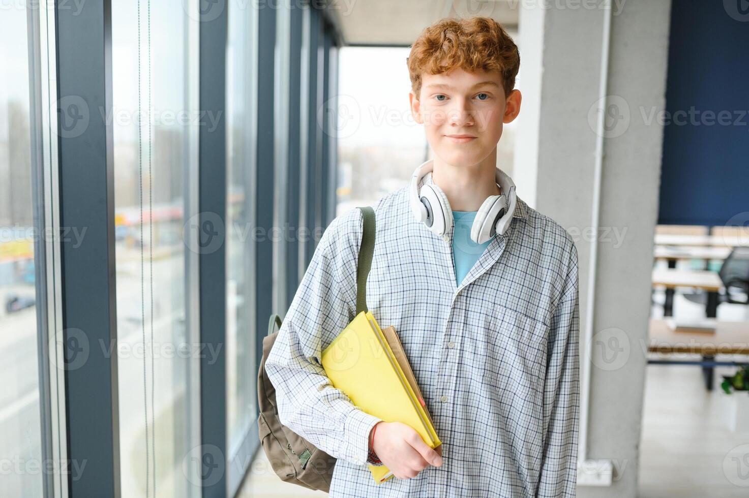 A young guy college student with a backpack is standing in the hall of the university photo