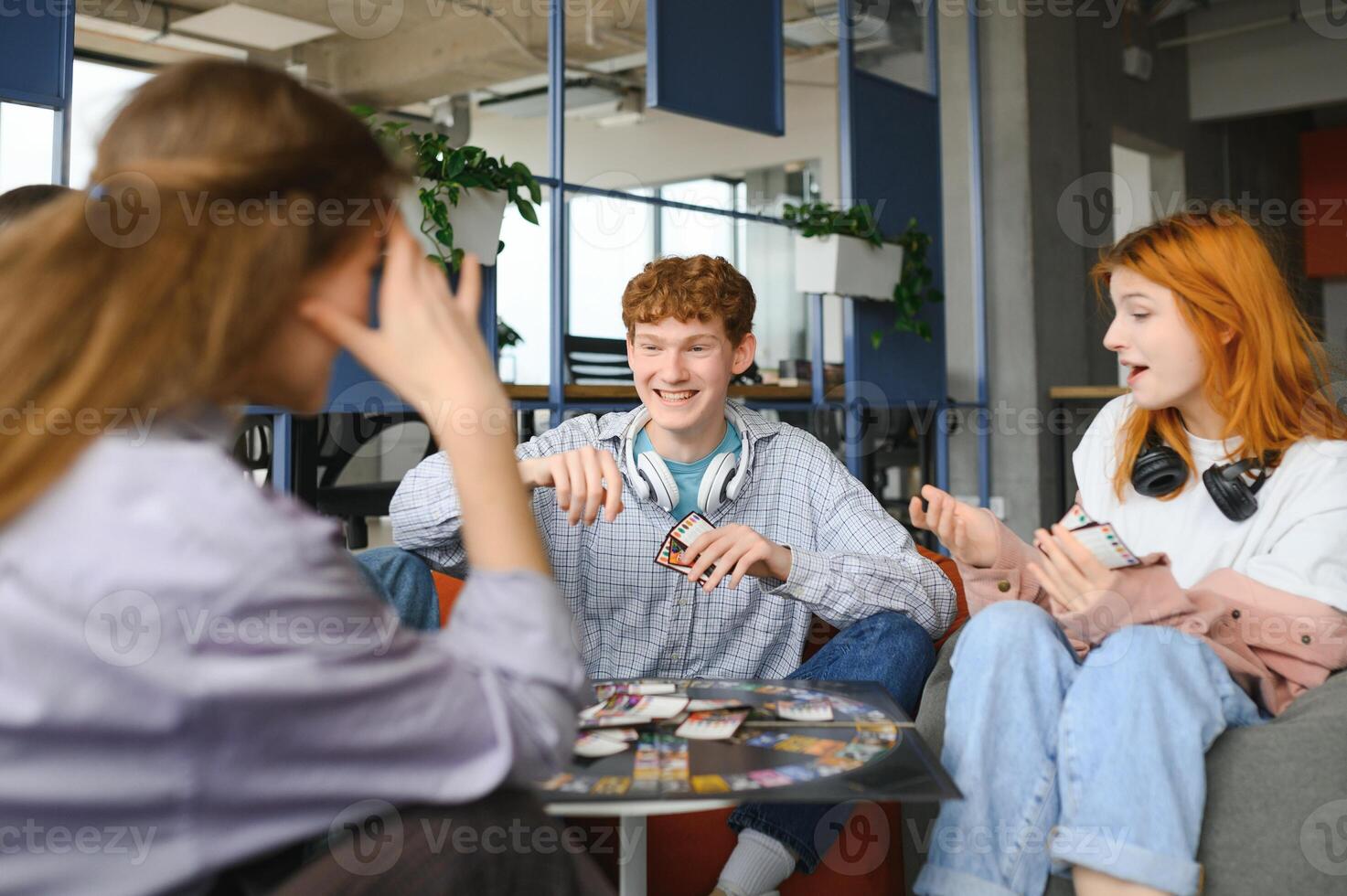 Group of creative friends sitting at wooden table. People having fun while playing board game photo