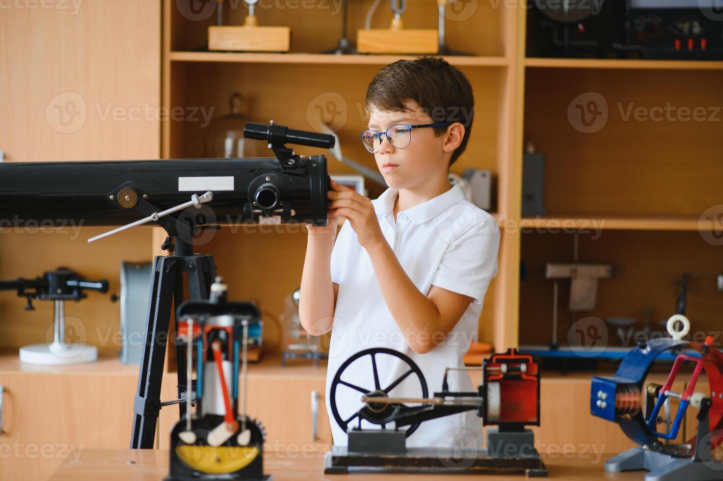 Physics lesson. A student at a desk with scientific instruments and a telescope photo