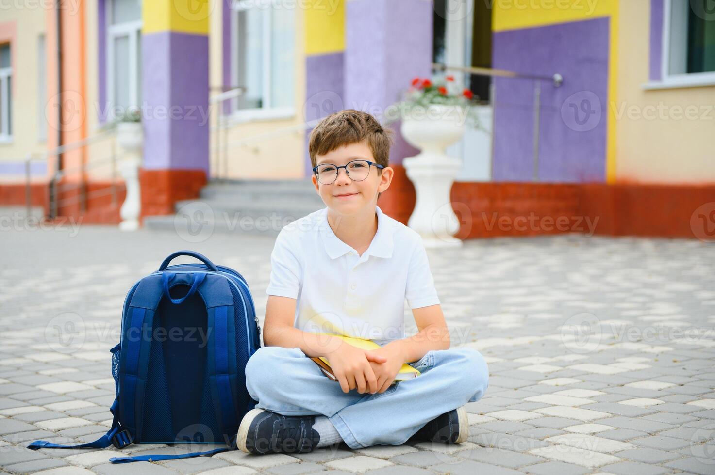 Portrait of a junior high school student sitting and reading a book near the school. Learning concept photo