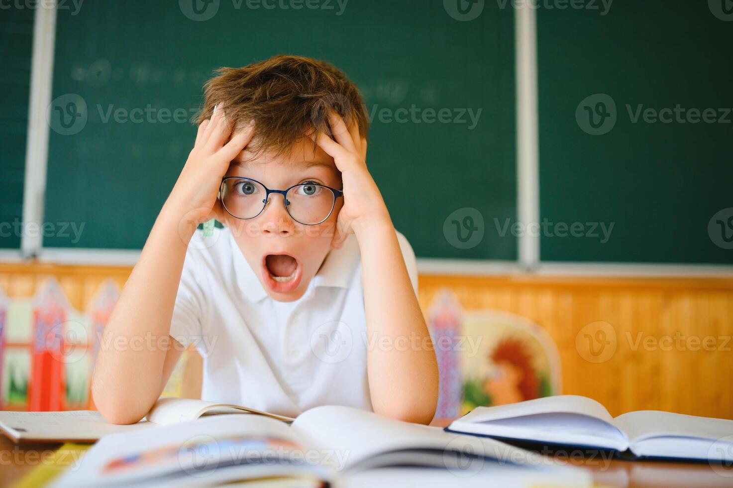 Portrait of a confused or surprised student at a desk in a classroom photo