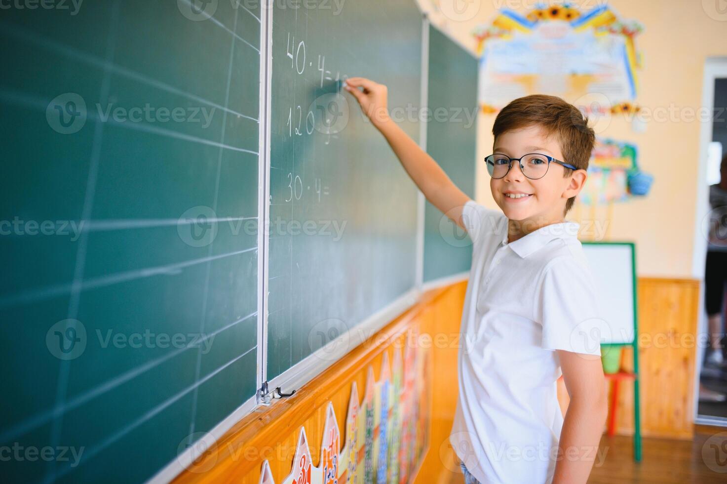 Funny schoolboy near the green school board in the classroom. Elementary school. Back to school photo