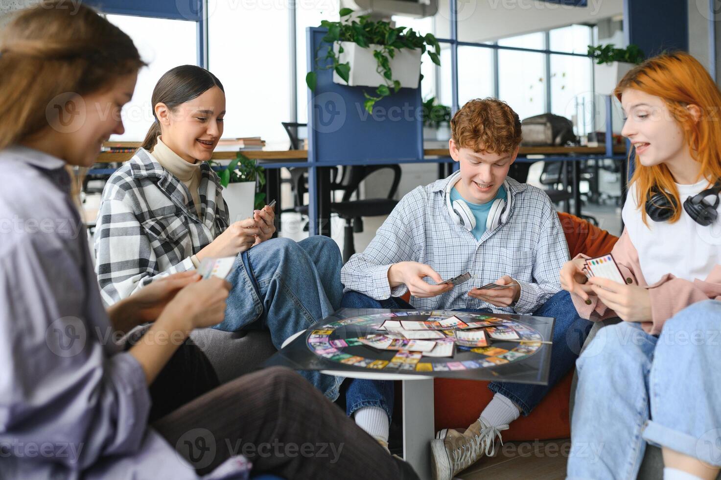 Group of creative friends sitting at wooden table. People having fun while playing board game photo