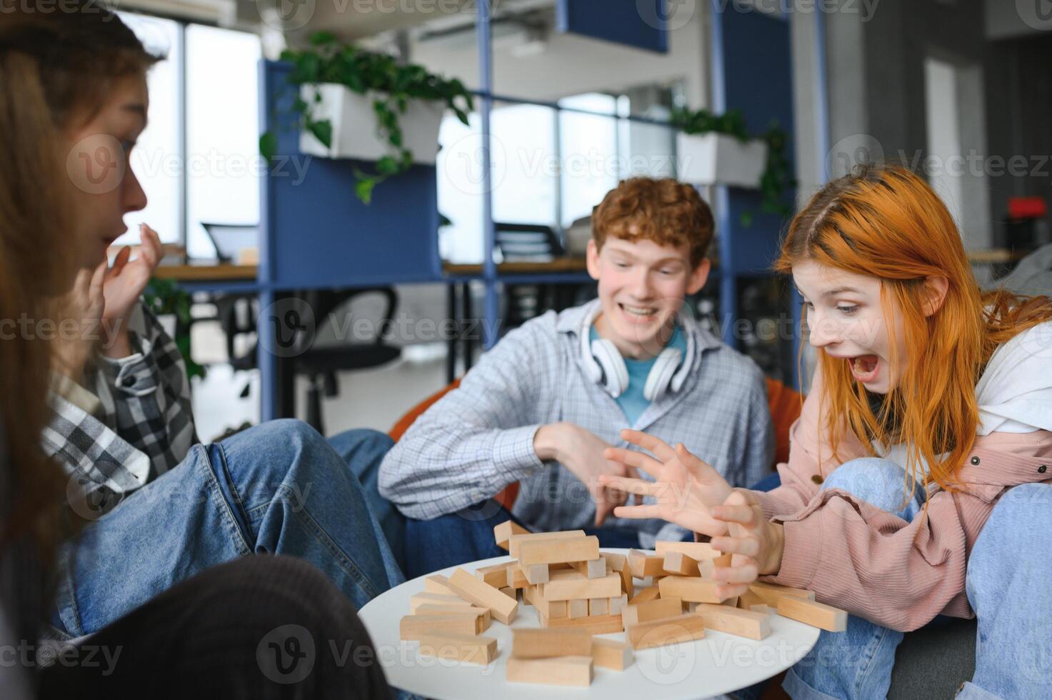 group of young friends playing board games together while sitting around table photo
