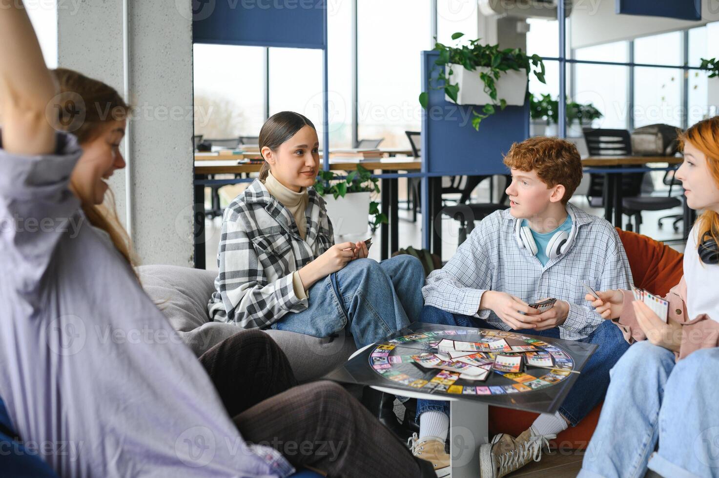 Group of creative friends sitting at wooden table. People having fun while playing board game photo