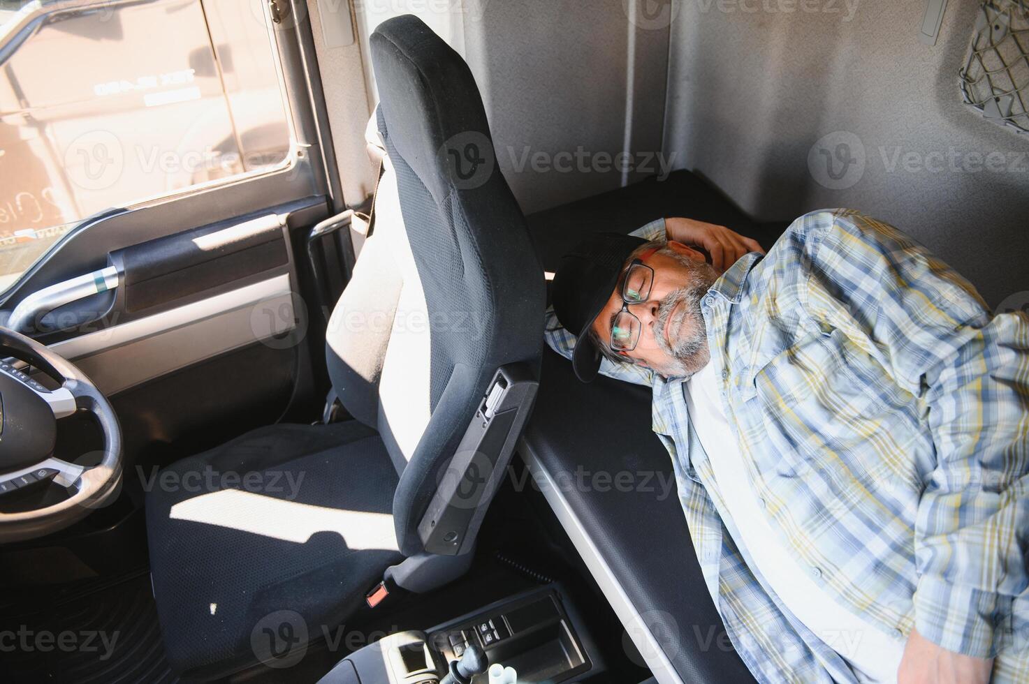 Truck driver sleeping in his cabin after working long routes overtime photo