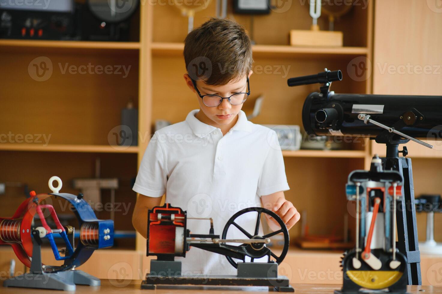 Physics lesson. A student at a desk with scientific instruments and a telescope photo