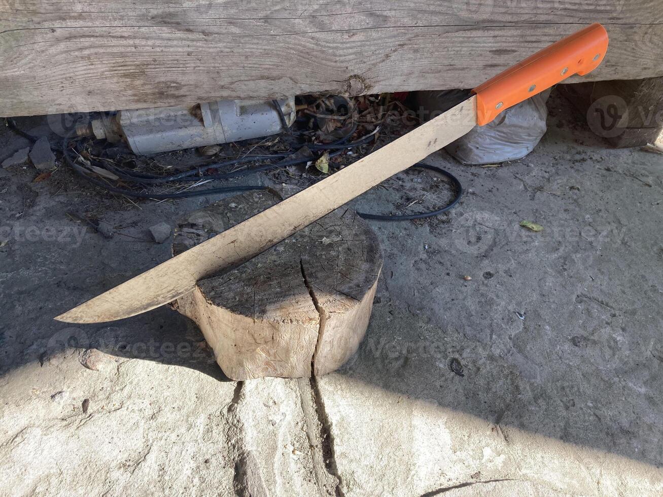 A machete stuck into a wooden stump photo