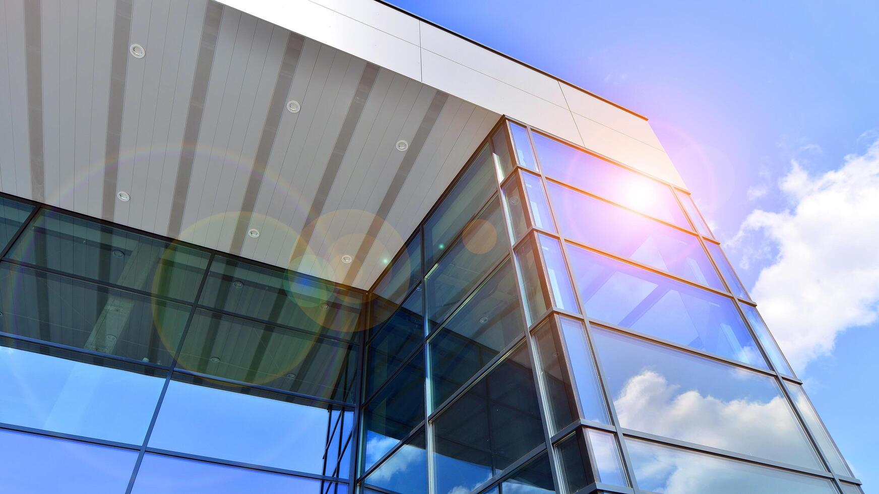Fragment of a modern building made of steel and glass. Abstract modern commercial architecture fragment. Walls made of shiny glass and steel under blue sky. photo
