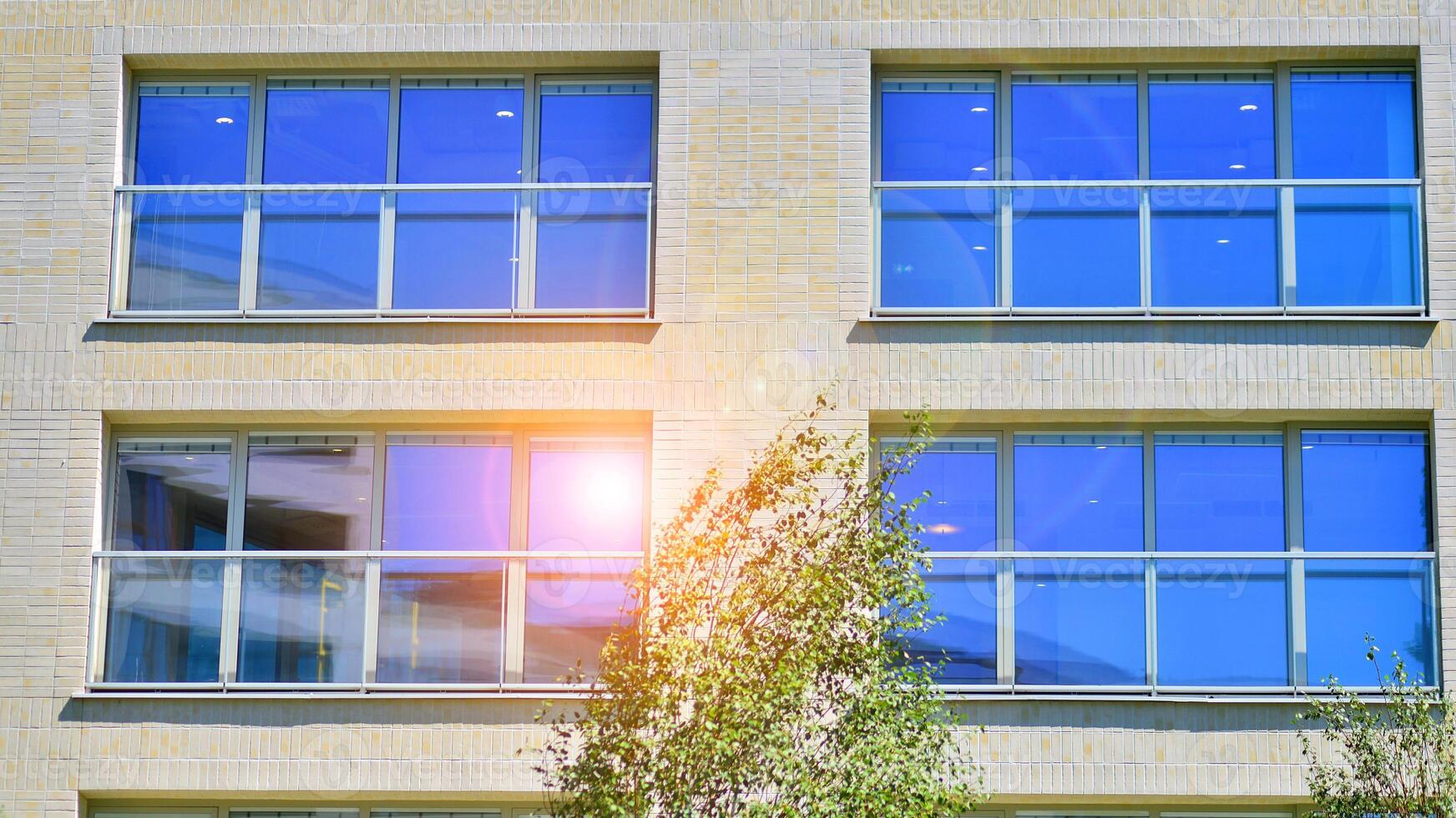 New modern block of flats in green area. Eco apartment building saving energy and fresh air concept. Green tree and new apartment building. The harmony of nature and modernity. photo