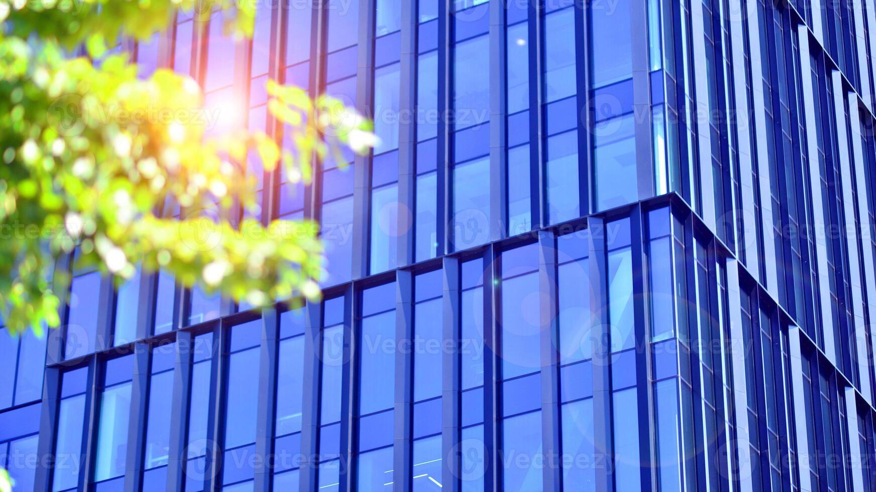 City life, urban landscape and ecology. Modern office complex with glass facades and smooth lines against backdrop of green trees, concept of modern architecture. Organically building into nature. photo