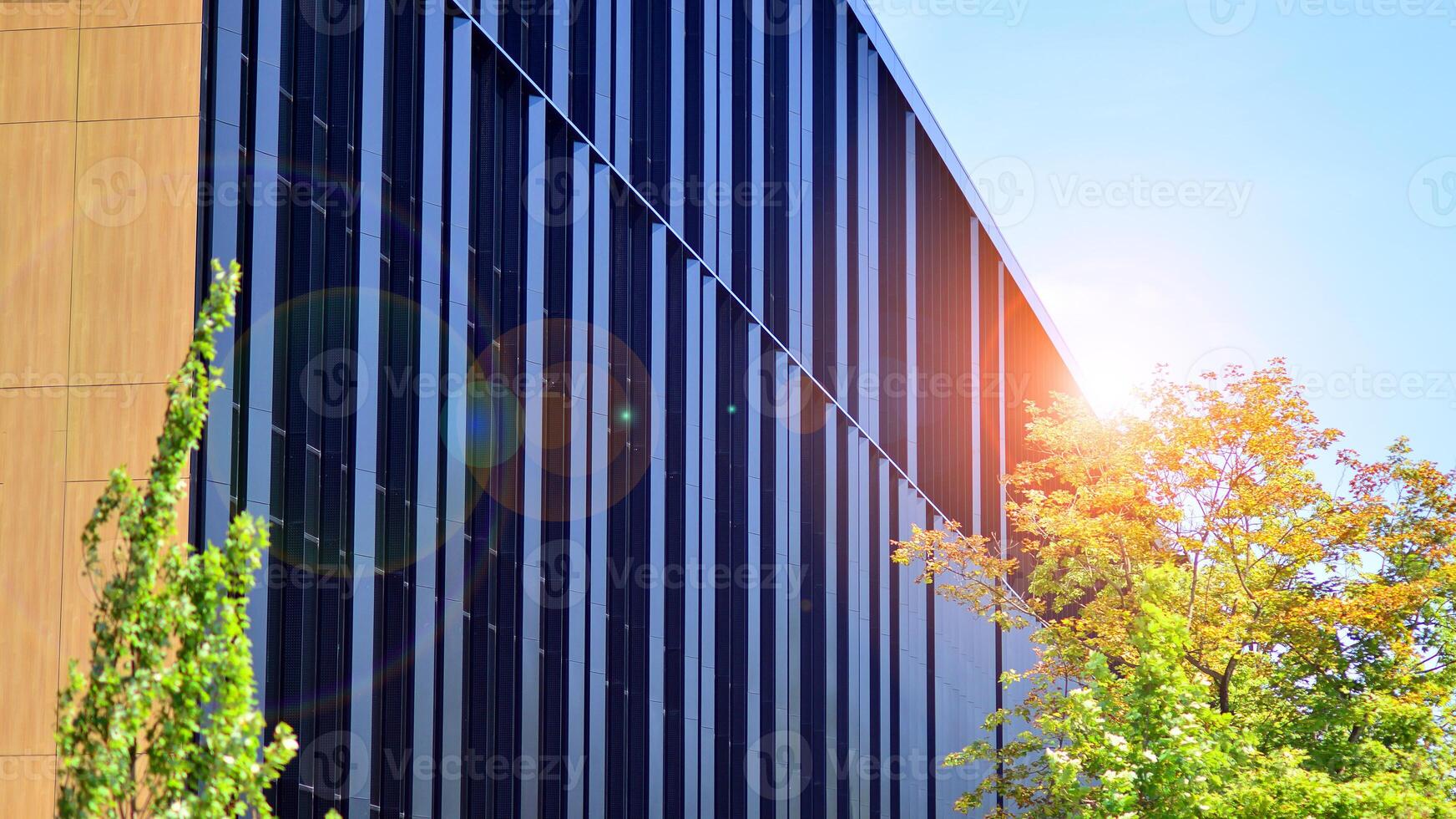 City life, urban landscape and ecology. Modern office complex with glass facades and smooth lines against backdrop of green trees, concept of modern architecture. Organically building into nature. photo