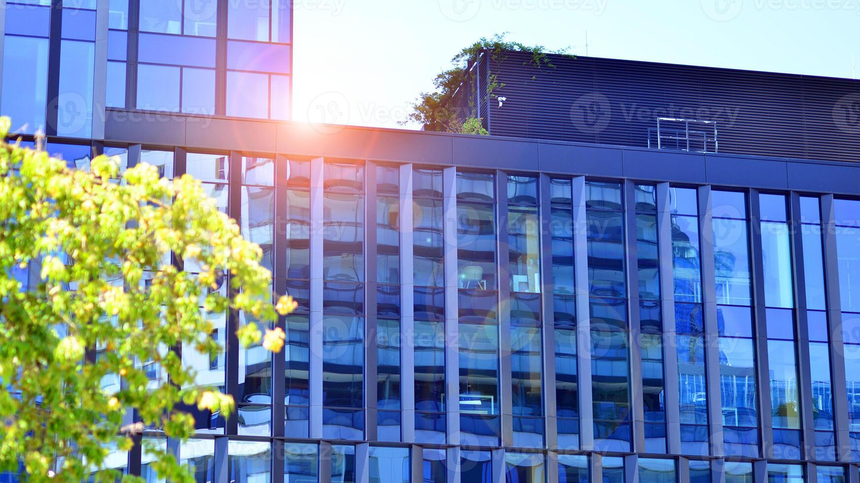 City life, urban landscape and ecology. Modern office complex with glass facades and smooth lines against backdrop of green trees, concept of modern architecture. Organically building into nature. photo