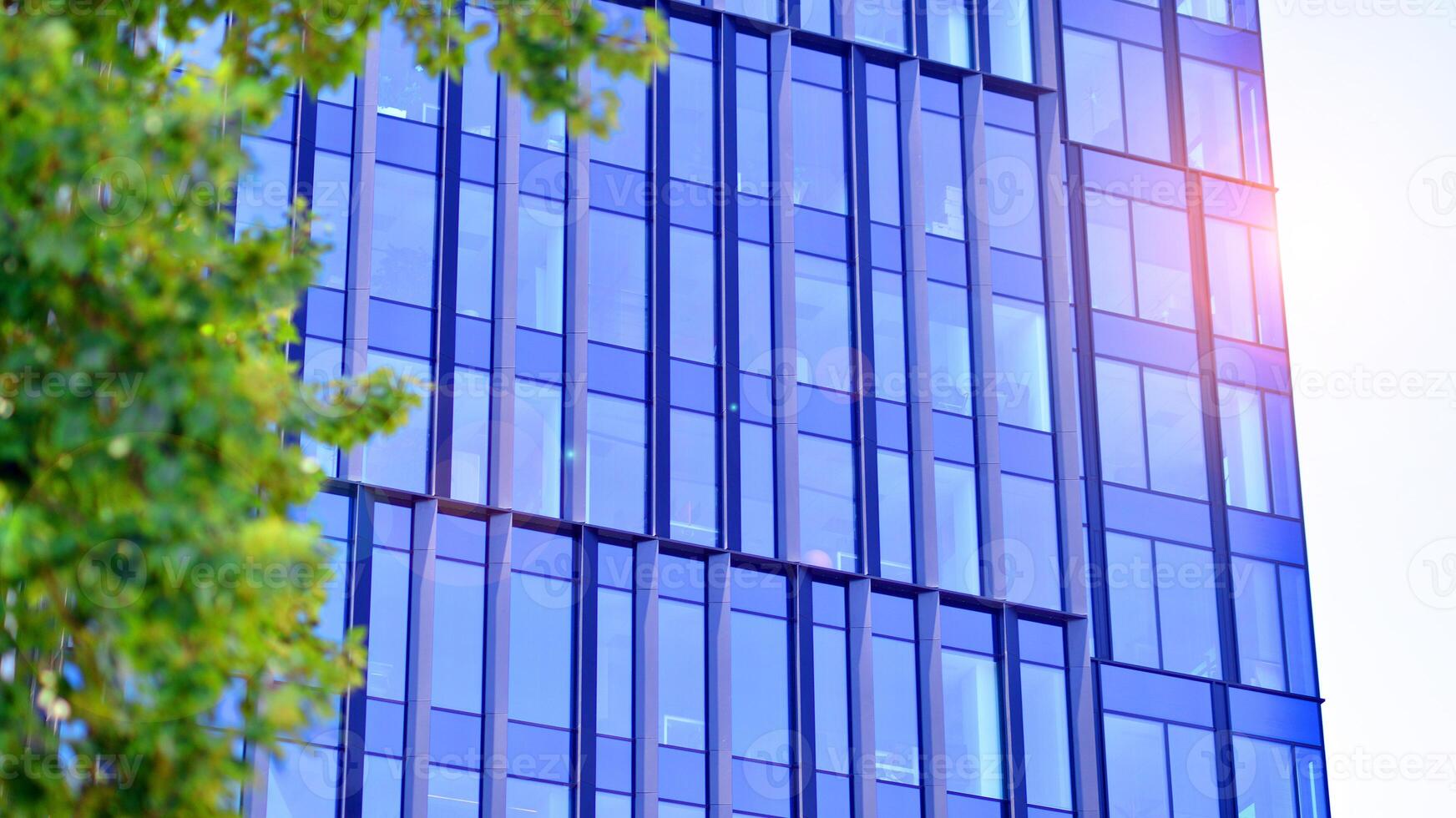City life, urban landscape and ecology. Modern office complex with glass facades and smooth lines against backdrop of green trees, concept of modern architecture. Organically building into nature. photo