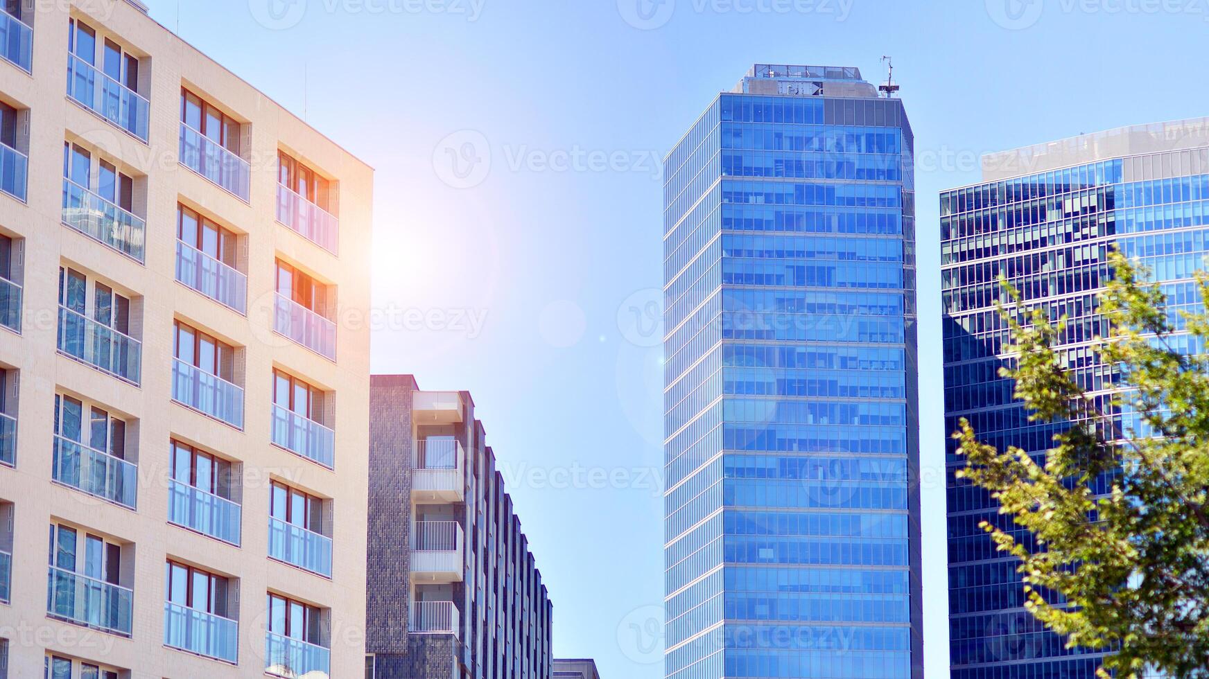 City life, urban landscape and ecology. Modern office complex with glass facades and smooth lines against backdrop of green trees, concept of modern architecture. Organically building into nature. photo