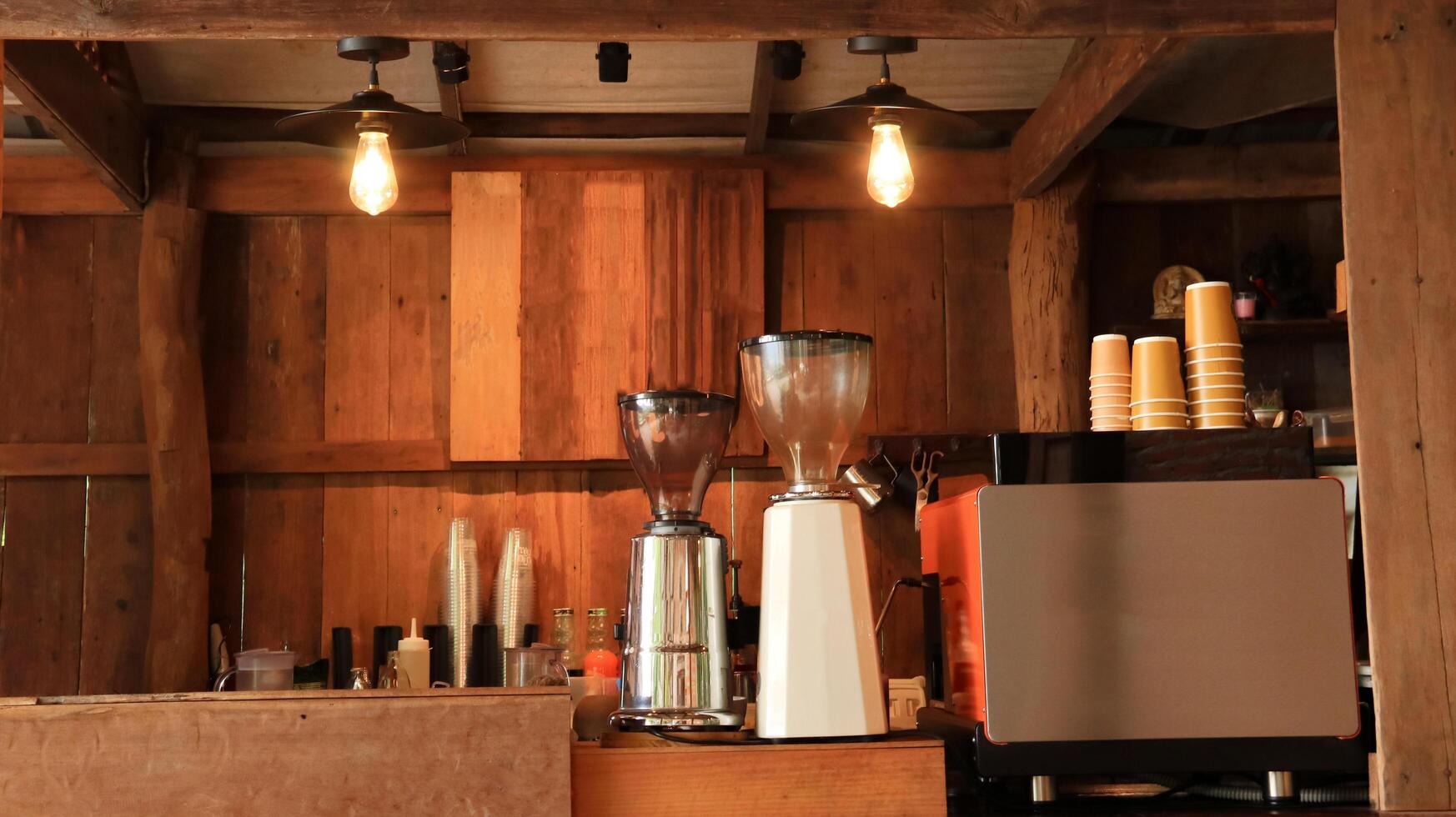 A well-equipped coffee machine along with brewing tools displayed in a coffee shop with warm brown wooden panels. photo