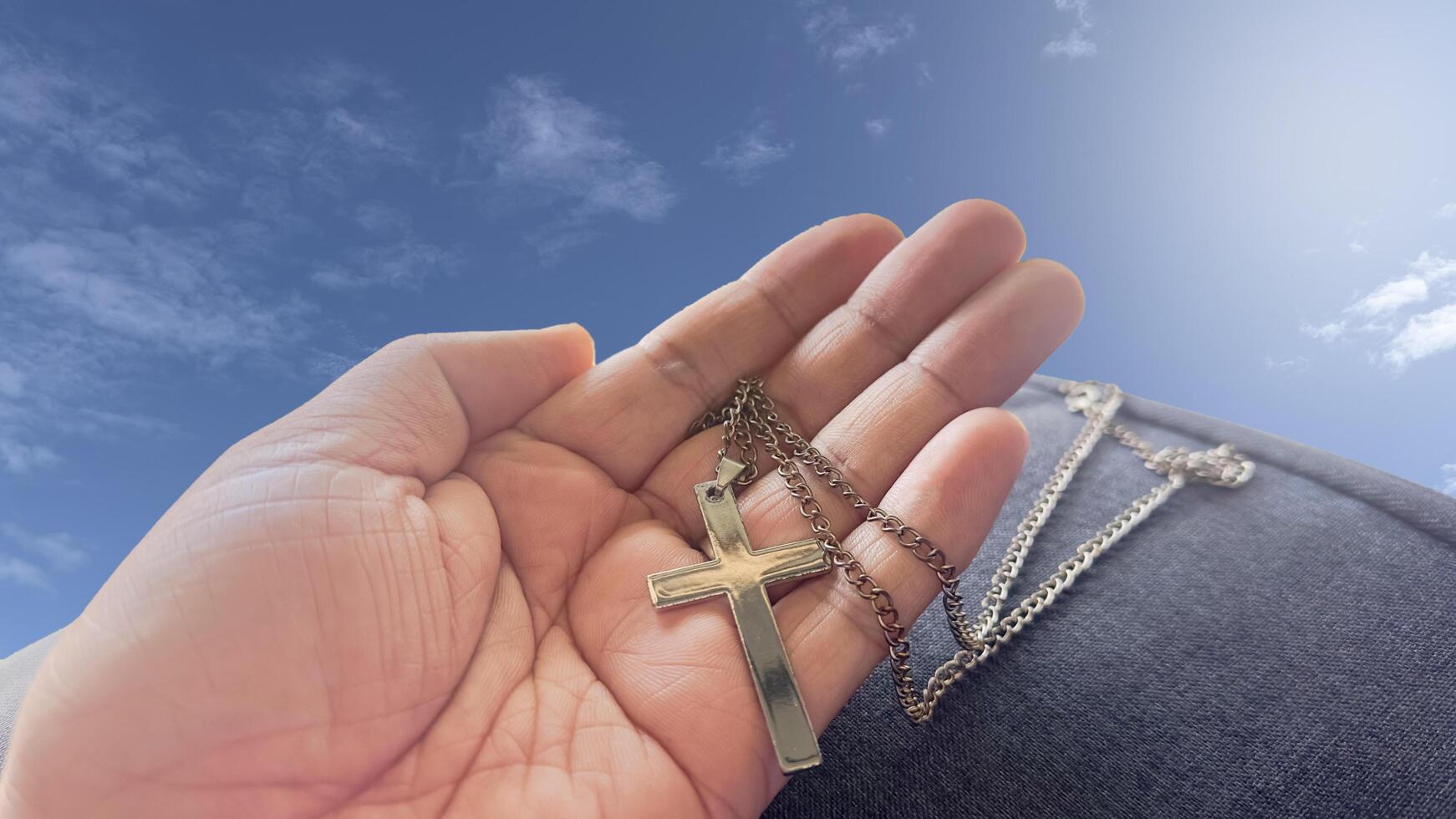 A brown wooden cross resting in an open palm, symbolizing the spreading of Jesus Christ's love to all. photo