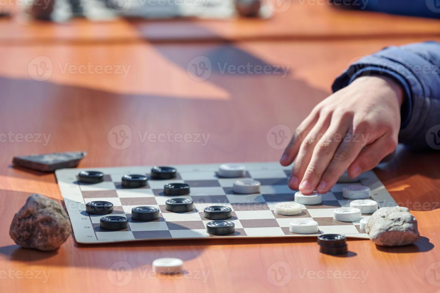 Outdoor checkers tournament on paper checkerboard on table, close up players hands photo