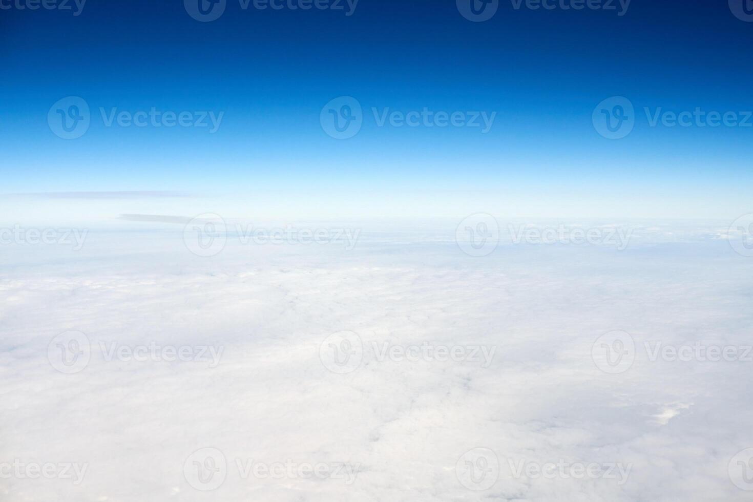 Over clouds aerial top view from aircraft window, thick white blue clouds looks like soft foam photo
