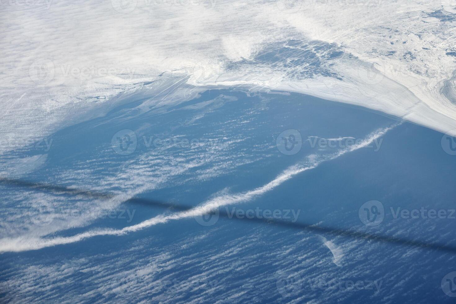 Aerial view from airplane window over clouds to frozen sea with north steam gas pipeline underwater photo