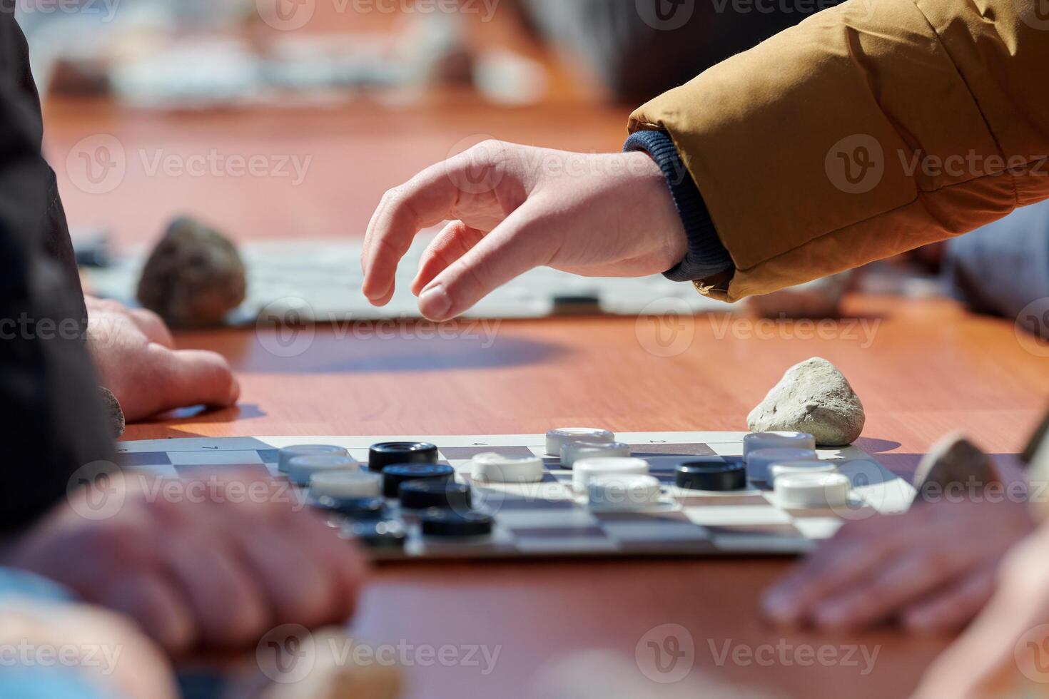 Outdoor draughts competition on paper checkerboard on table, close up players hands photo