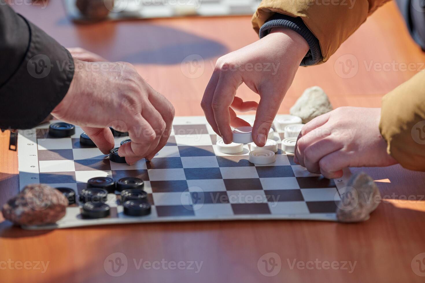 Outdoor checkers tournament on paper checkerboard on table, close up players hands photo
