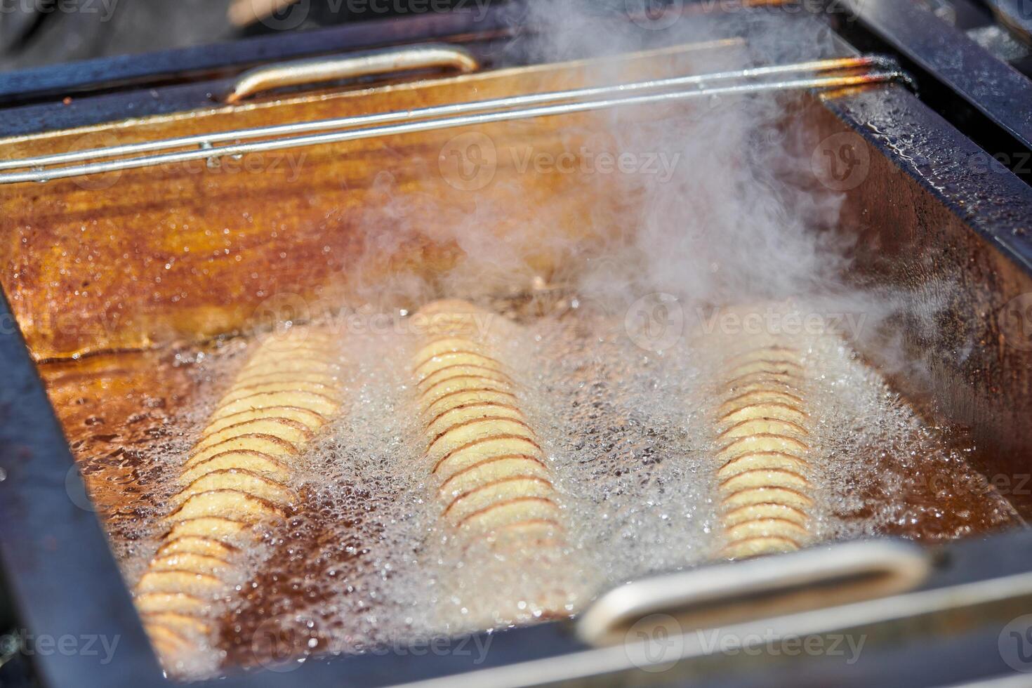 Cooking spiral fried potato in boiling oil, rich in fat and calories fast food, unhealthy delicious photo