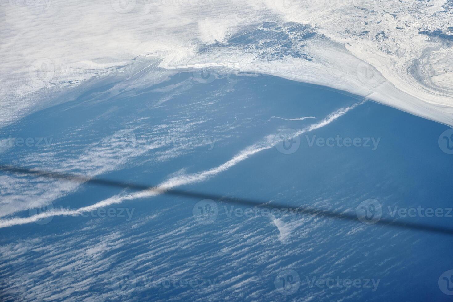 Aerial view from airplane window over clouds to frozen sea with north steam gas pipeline underwater photo