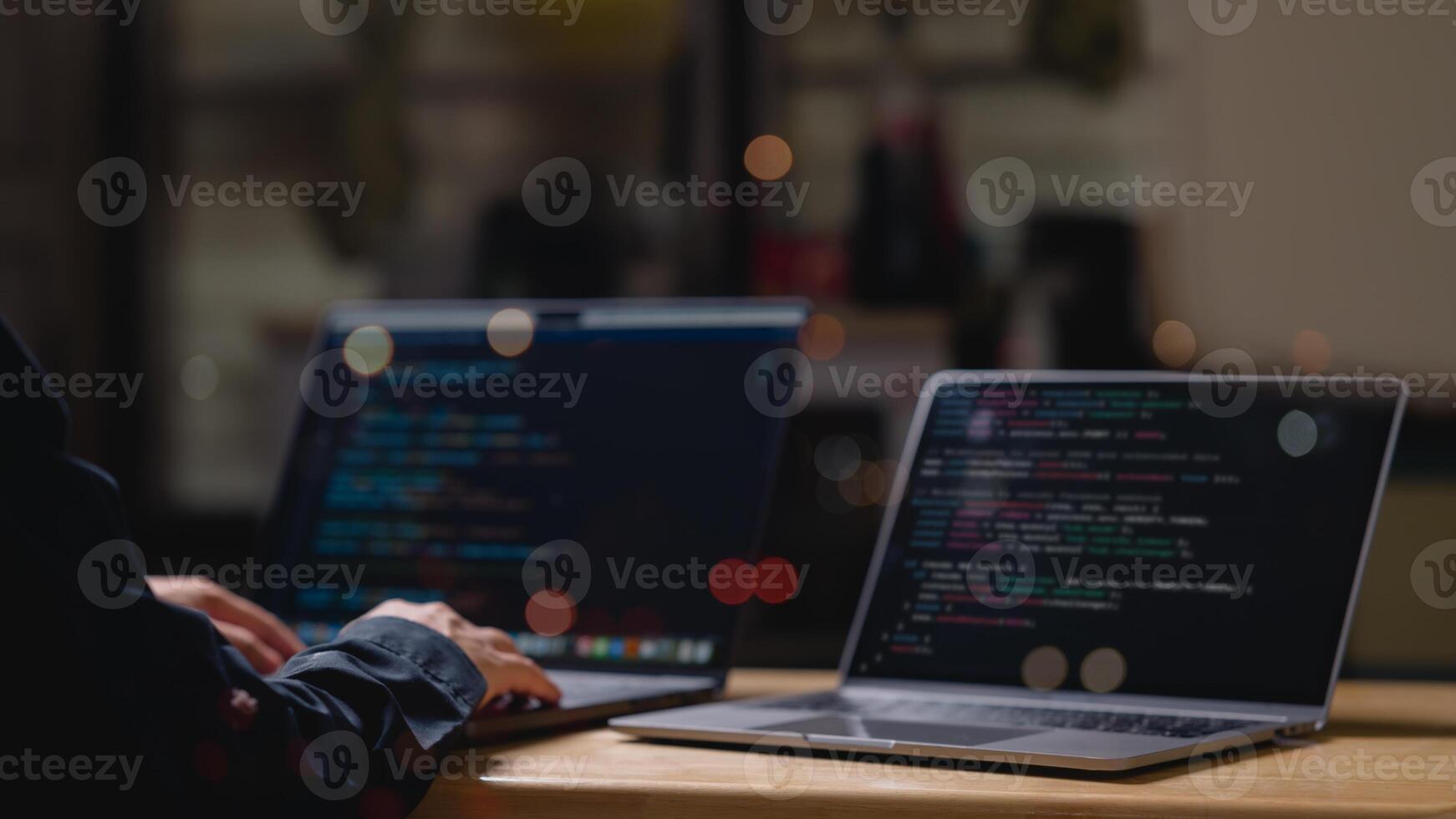 A person is typing coding on a laptop computer with a black screen. The laptop is open to a webpage with a lot of code. The person is focused on the task at hand photo