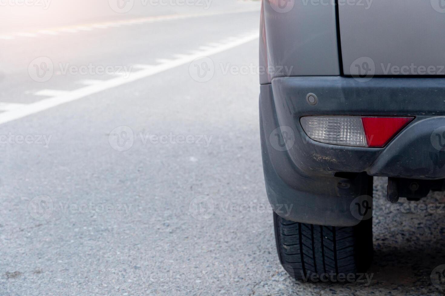 Close up of car back bumper with red light on the asphalt road. Blurred of asphalt road with line and light. photo
