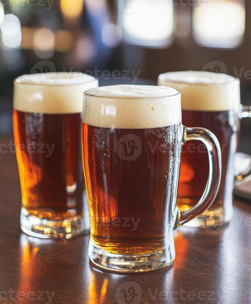 Cold beers with frothy tops on a wooden bar table during happy hour photo