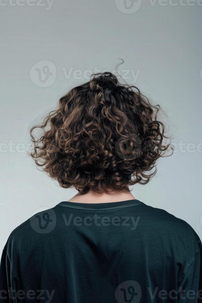 Young man with curly hair facing away in a minimalist studio photo