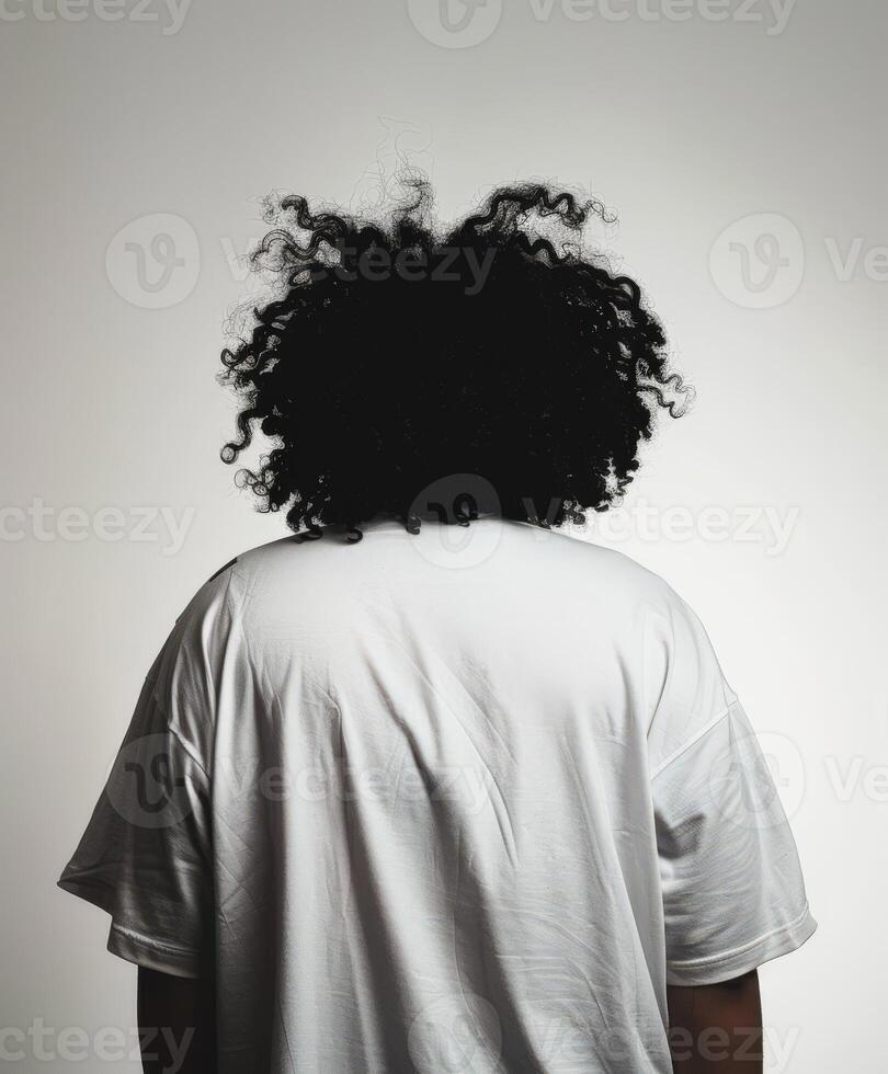 Young man with curly hair facing away against a plain backdrop photo