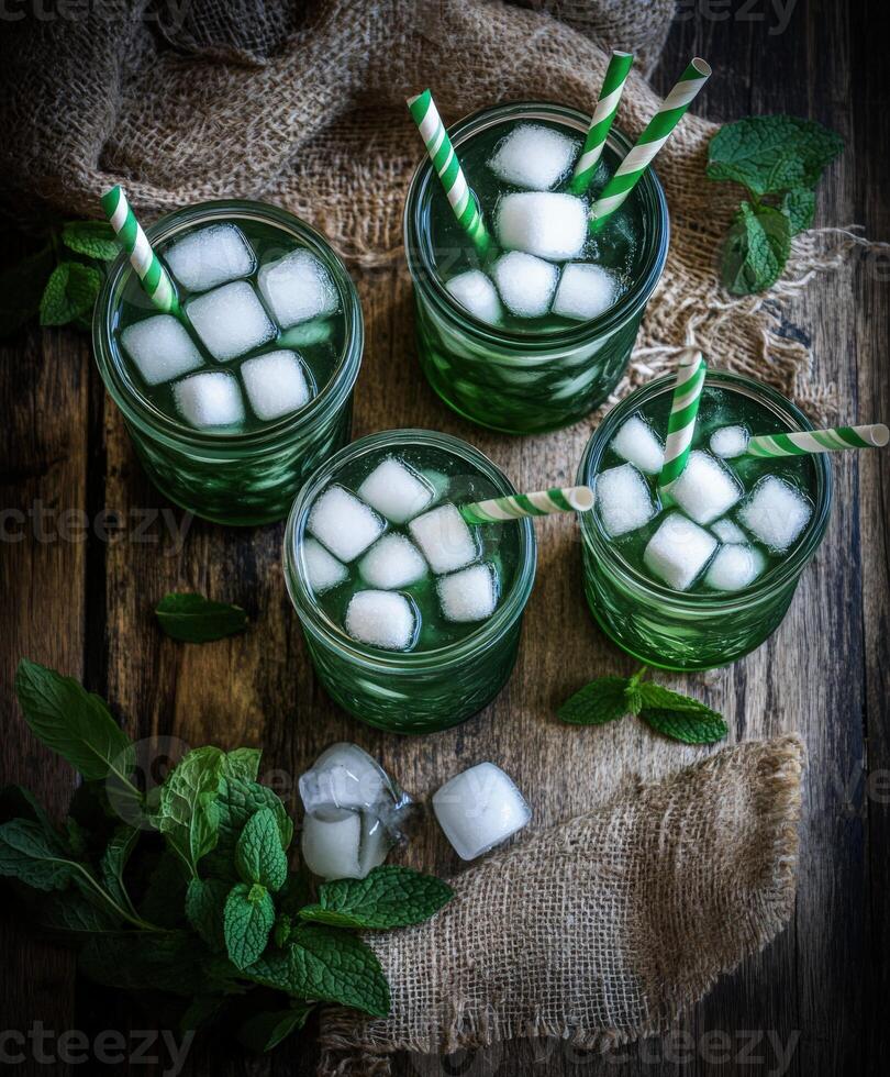 Refreshing green mint lemonade with ice cubes and straws on a rustic table photo