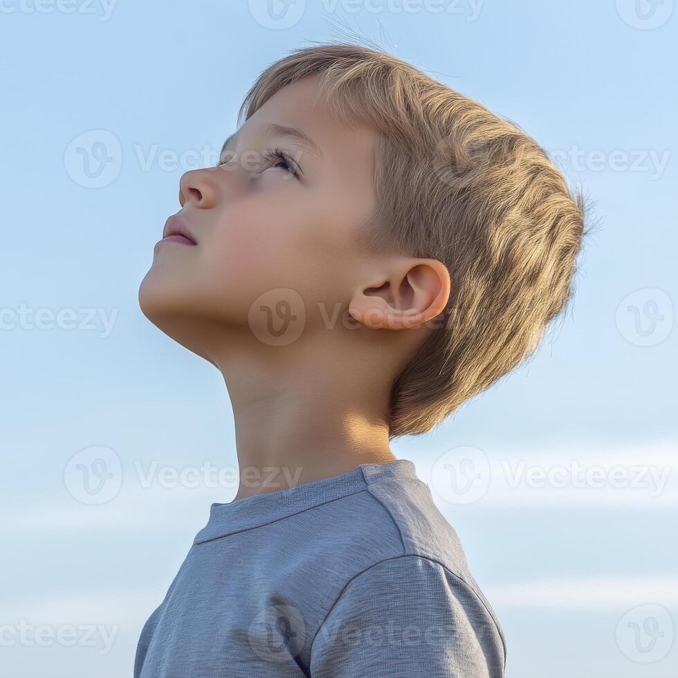 High school boy gazing thoughtfully at the clear blue sky outdoors photo