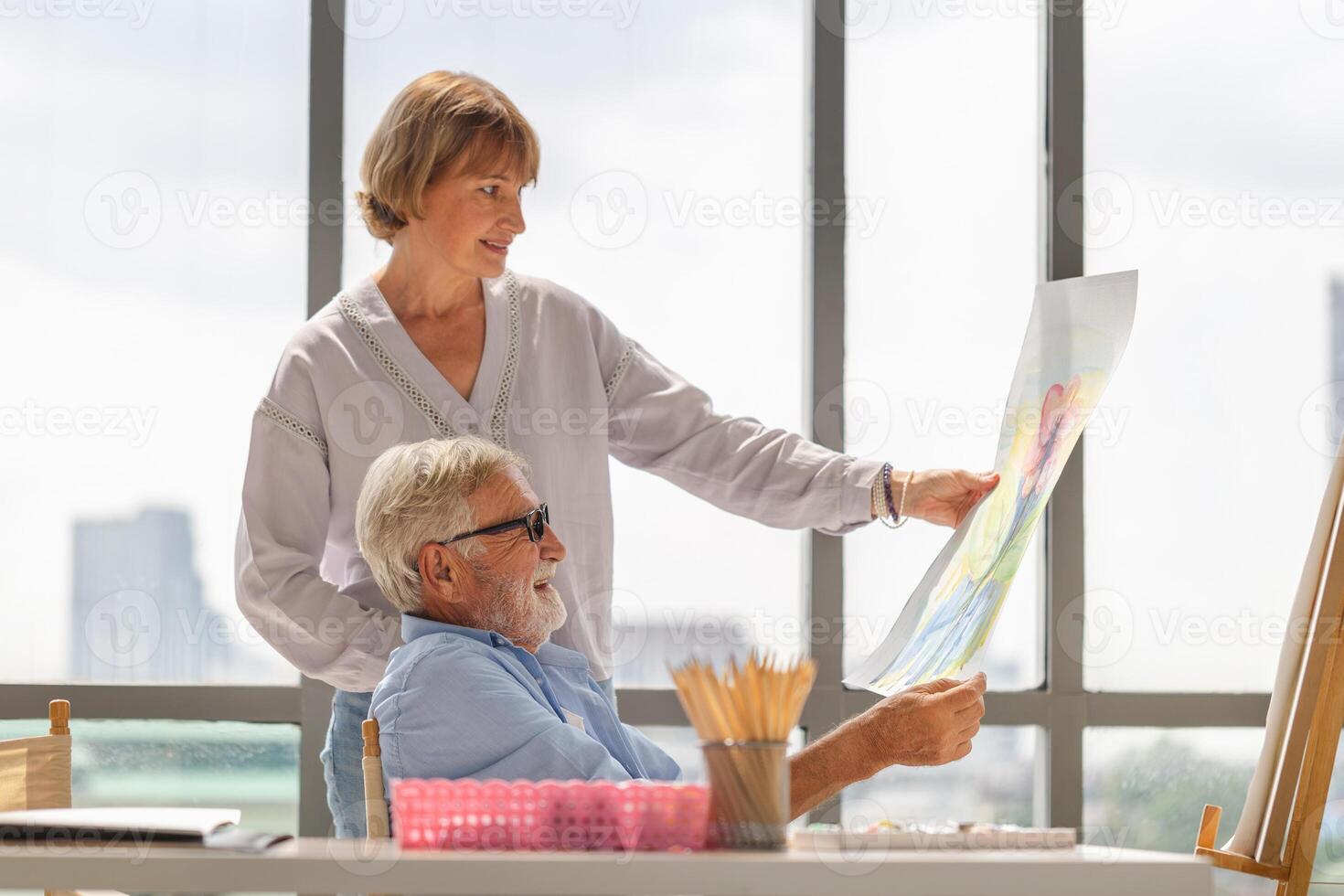 Senior couple spending time together in the living room, Happy senior couple painting on a canvas in living room, Caucasian couple drawing on a canvas, Happy retirement concepts photo