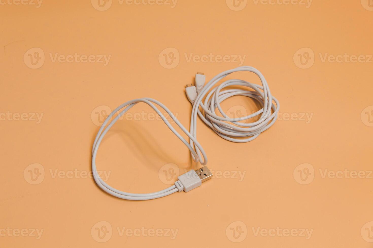 USB cable for smartphone on beige background, White usb cable on beige background, computer peripherals connector or smartphone recharge supply photo