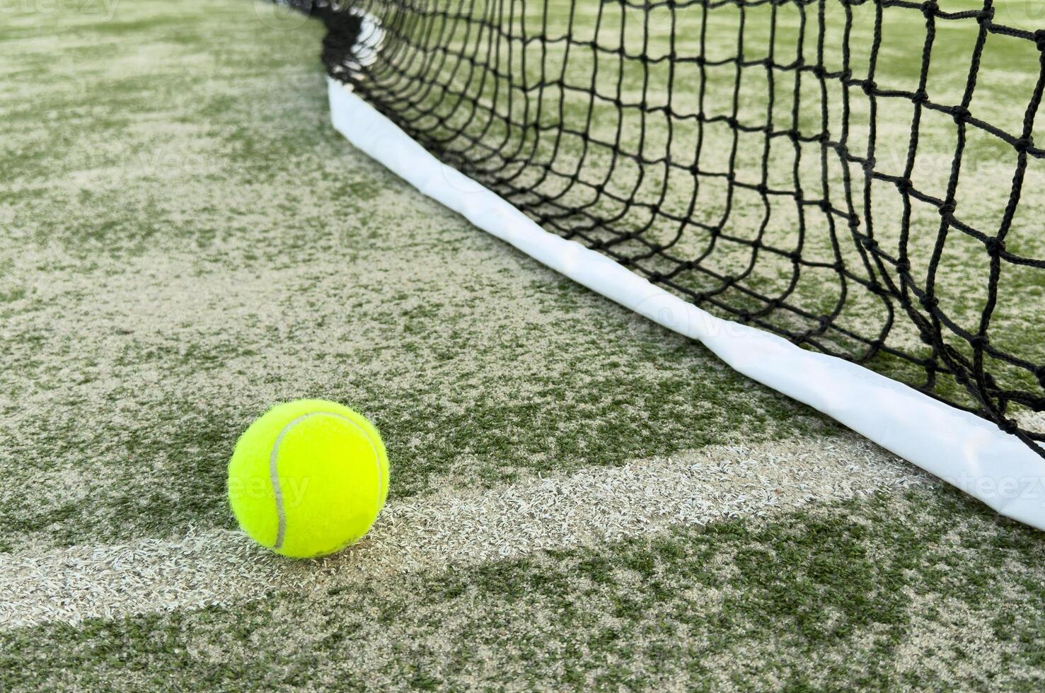 Tennis or paddle balls on synthetic grass of paddle court with net on the background photo