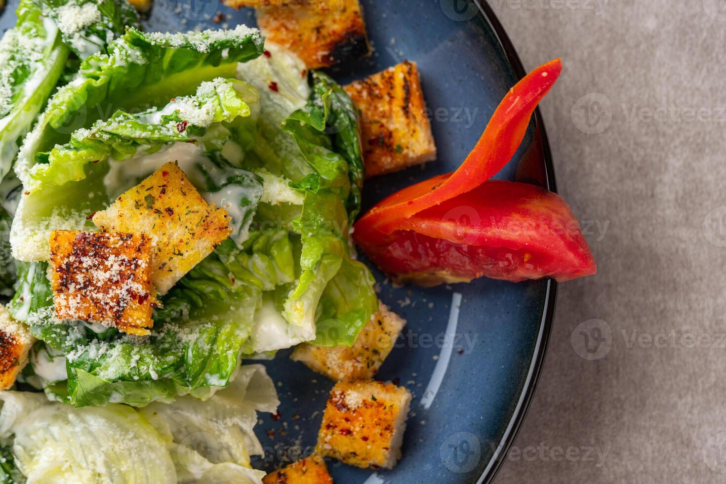 Caesar salad is a green salad of romaine lettuce and croutons dressed with mustard, Parmesan cheese, and garlic bread. photo