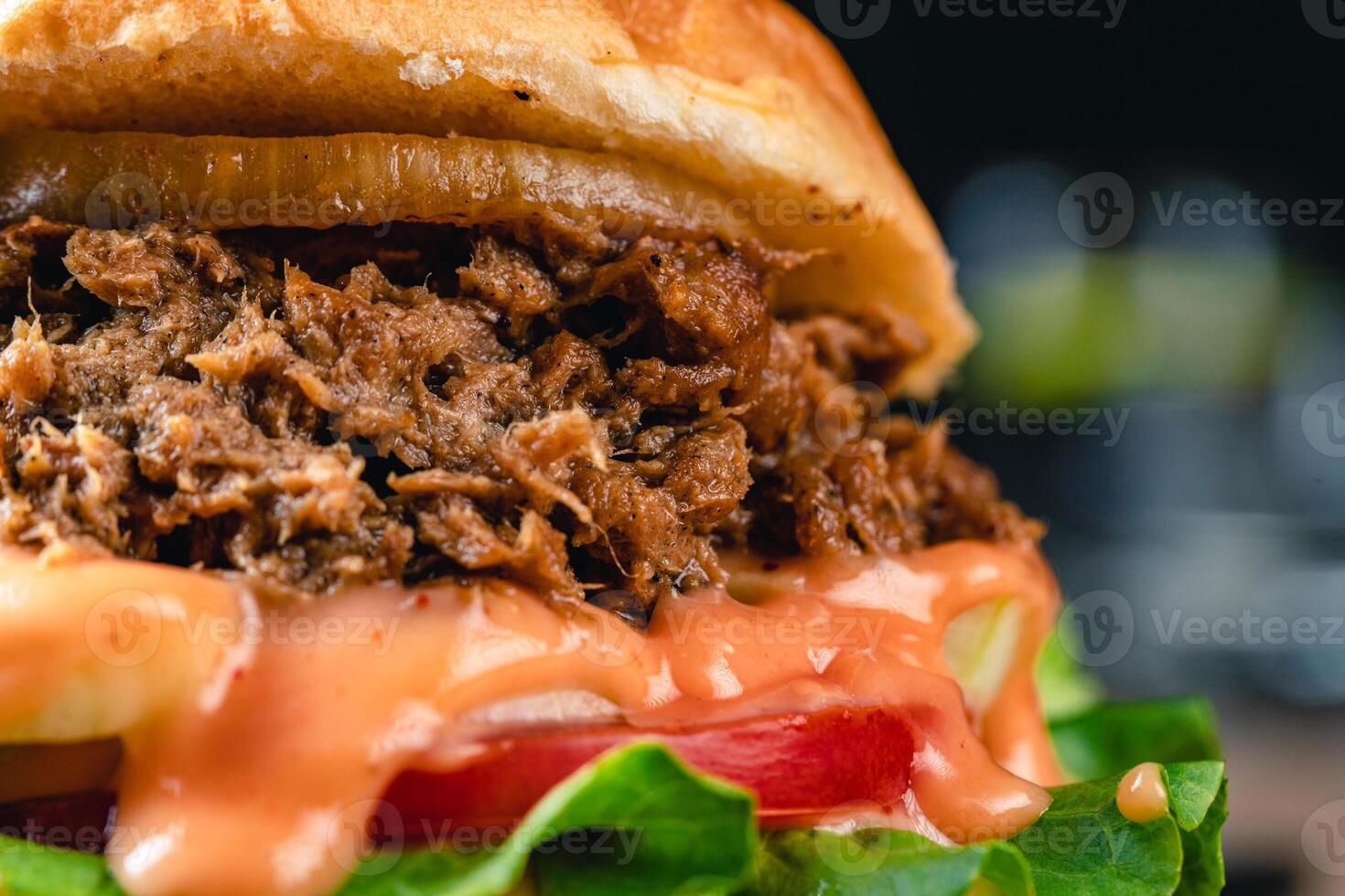 Tasty grilled tuna burger or sandwich with lettuce, tomato, onion rig and mayonnaise served on wooden table. dark mood. photo