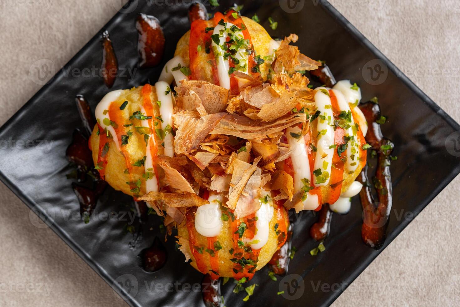 Takoyaki is a ball-shaped Japanese snack made of a wheat flour-based batter and cooked in a special molded pan photo