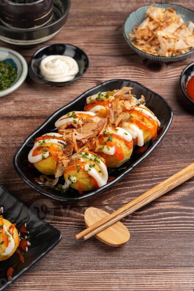 Takoyaki is a ball-shaped Japanese snack made of a wheat flour-based batter and cooked in a special molded pan photo