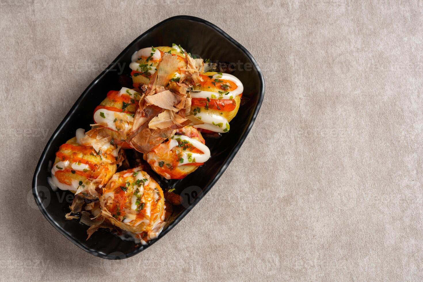 Takoyaki is a ball-shaped Japanese snack made of a wheat flour-based batter and cooked in a special molded pan photo