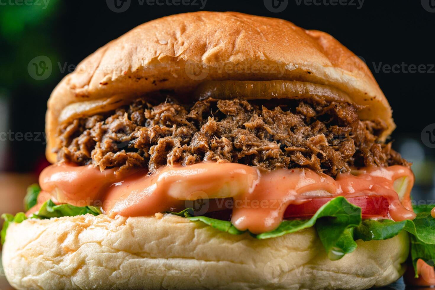 Tasty grilled tuna burger or sandwich with lettuce, tomato, onion rig and mayonnaise served on wooden table. dark mood. photo