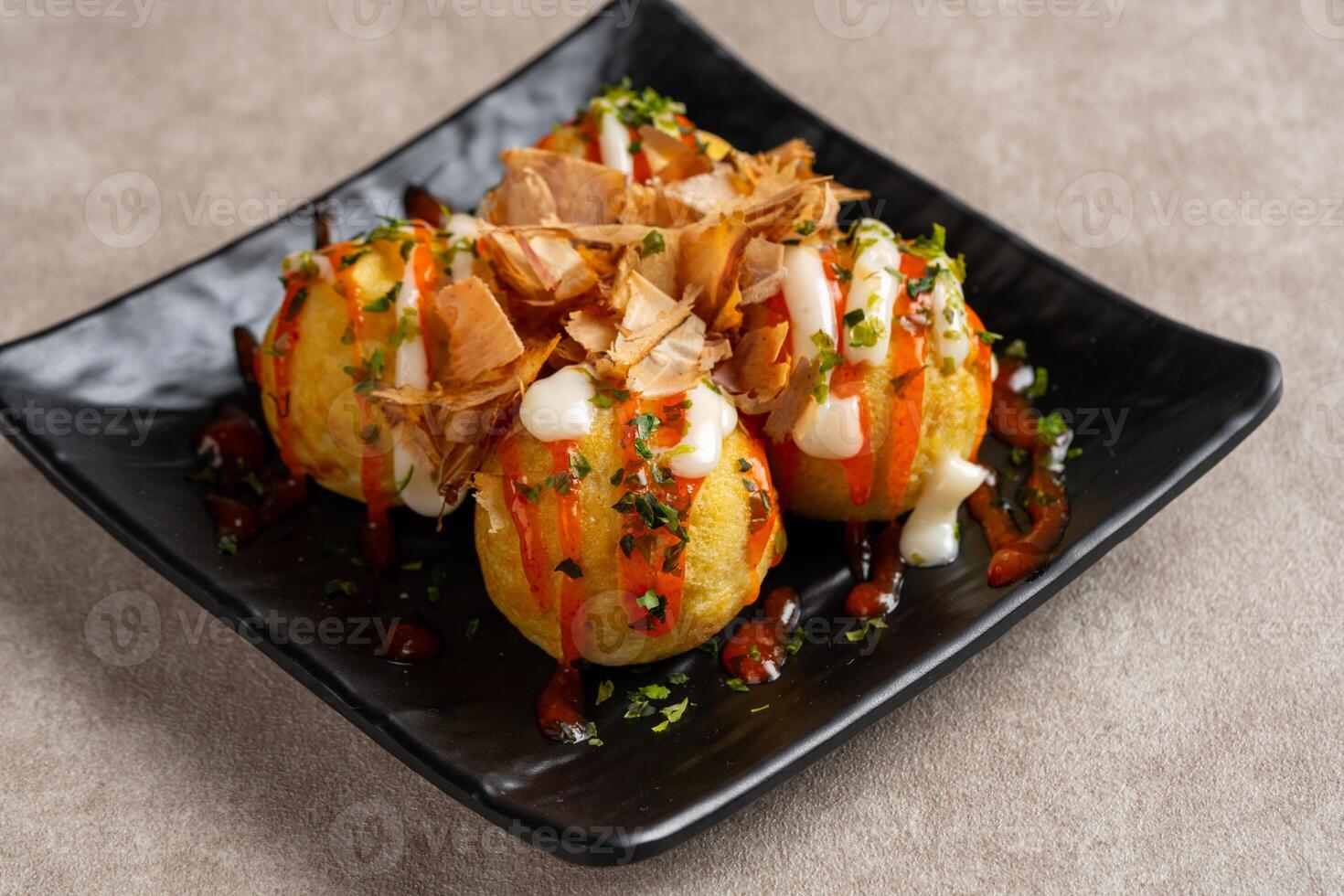 Takoyaki is a ball-shaped Japanese snack made of a wheat flour-based batter and cooked in a special molded pan photo