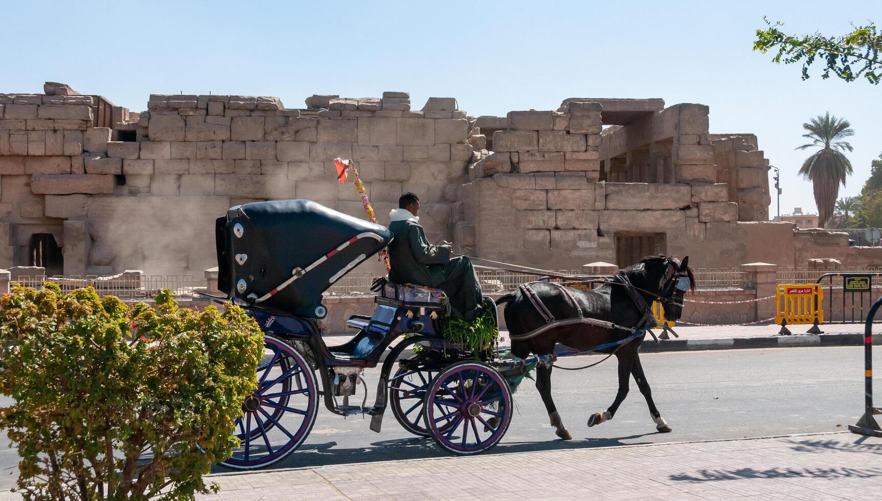 EGYPT, KARNAK - MARCH 01, 2019 a cart with a horse for walking with tourists against the backdrop of the temple complex in Karnak, Egypt photo