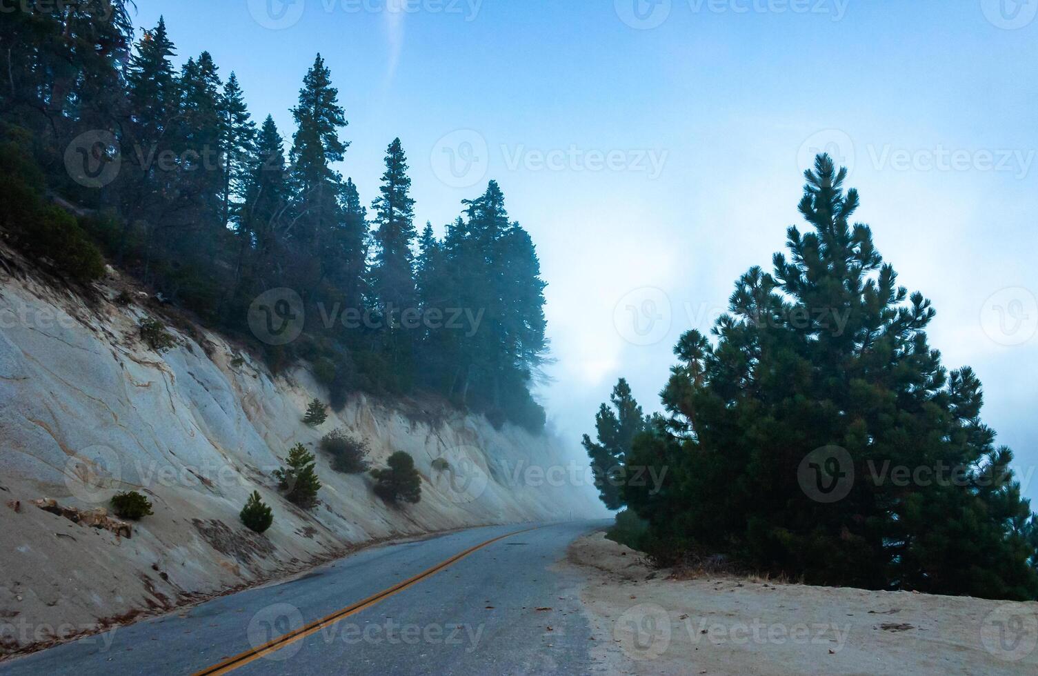 Mountain pass - view from the top of the mountain, coniferous trees in clouds on the slopes of the Sierra Nevada mountains, California, USA photo